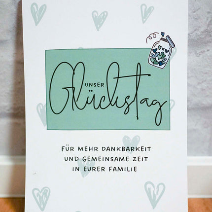 Liebevoll gestalteter Abreißblock Unser Glückstag für Familien auf einem Holztisch